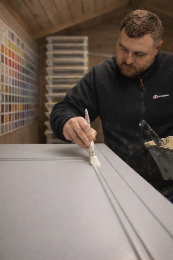 paul barber jnr painting a kitchen door in the workshop